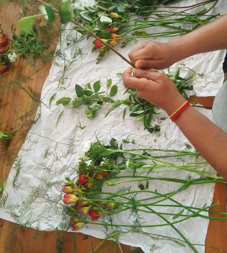 les mains dans les fleurs françaises et de saison posées sur une table.